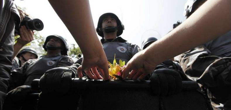 manifestante coloca flor no escudo da policia militar