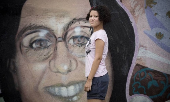 MC Lidi com o grafite de Marina da Penha ao fundo, na Praça das Nações Unidas, em Nova Iguaçu - Márcia Foletto / Agência O Globo 
