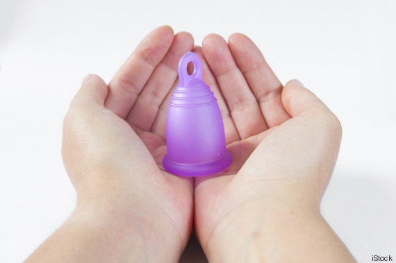 Studio shot of woman hands holding a standing menstrual cup, on white background.