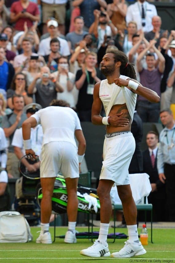 Germany's Dustin Brown (R) slaps a tattoo on his flank after beating Spain's Rafael Nadal (L) in their men's singles second round match on day four of the 2015 Wimbledon Championships at The All England Tennis Club in Wimbledon, southwest London, on July 2, 2015. Brown won 7-5, 3-6, 6-4, 6-4.  RESTRICTED TO EDITORIAL USE  --   AFP PHOTO / GLYN KIRK        (Photo credit should read GLYN KIRK/AFP/Getty Images)