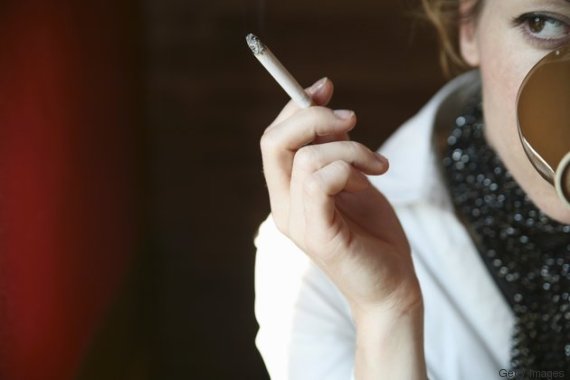 Woman sitting in cafe drinking coffee and smoking a cigarette