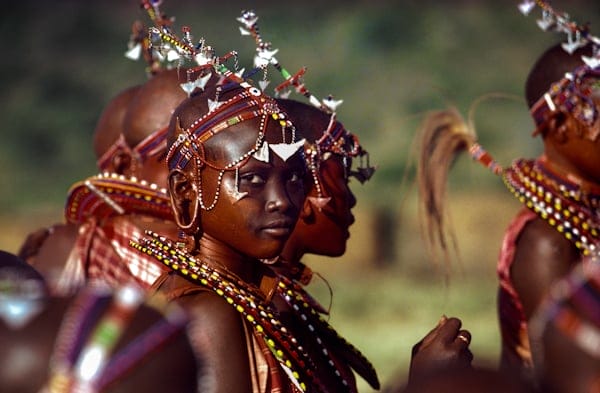 Maasai girls from Kenya attend the Eunoto ceremony – the passage of their warrior boyfriends into elderhood. Their beaded collars and headbands are designed to bounce rhythmically to enhance their body movements. Traditionally a Maasai girl is allowed to select three lovers from among the warriors. This is the one time in her life when she is allowed to enjoy freely chosen relationships. 1985