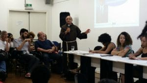 Silvio Caccia Bava (à esq. de camisa escura, sentado) durante fala do frei David