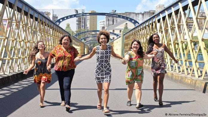 5 mulheres correndo e sorrindo em uma ponte, elas são do partido JUNTAS