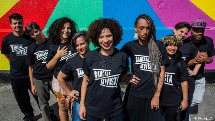 grupo de jovens vestido com camisas preta escrito ativistas