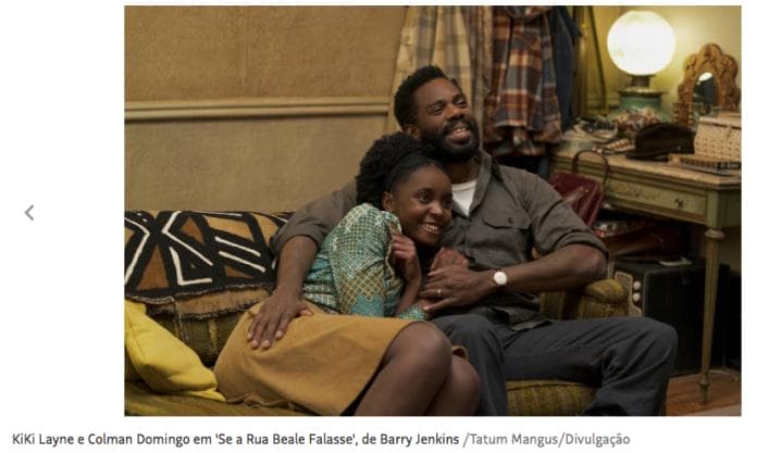 cena do filme “Se a Rua Beale Falasse” com dois atores negros sentados ao sofá abraçados e sorrindo