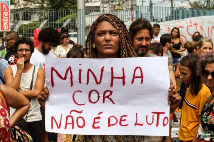 Mulher negra segurando cartaz escrito "minha cor não é de luto"