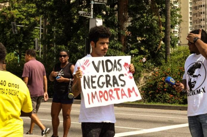 Famoso youtube Spartakus segurando cartaz escrito "Vidas Negras Importam"