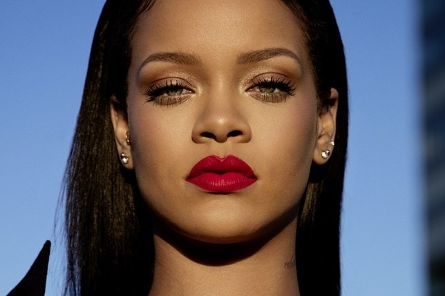 Rihanna- mulher negra, de cabelo liso preto e olhos verdes, usando batom vermelho.