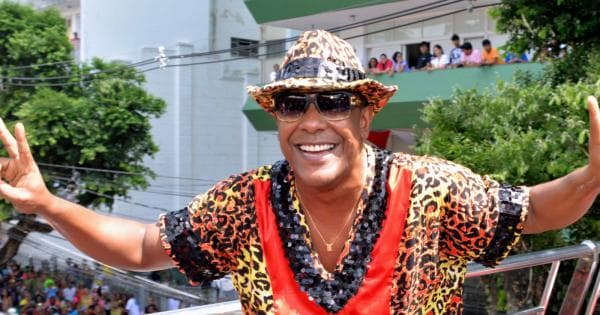 Márcio Victor - homem negro usando, óculos de sol,  camiseta e chapéu colorido- em pé sorrindo 