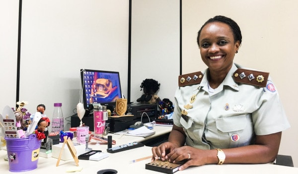 Major Denice Santiago - mulher negra de cabelo, preso, usando uniforme de major- sentada diante de uma mesa de escritório 