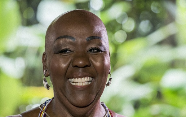 Virgínia Rodrigues - mulher negra, careca- em pé sorrindo 
