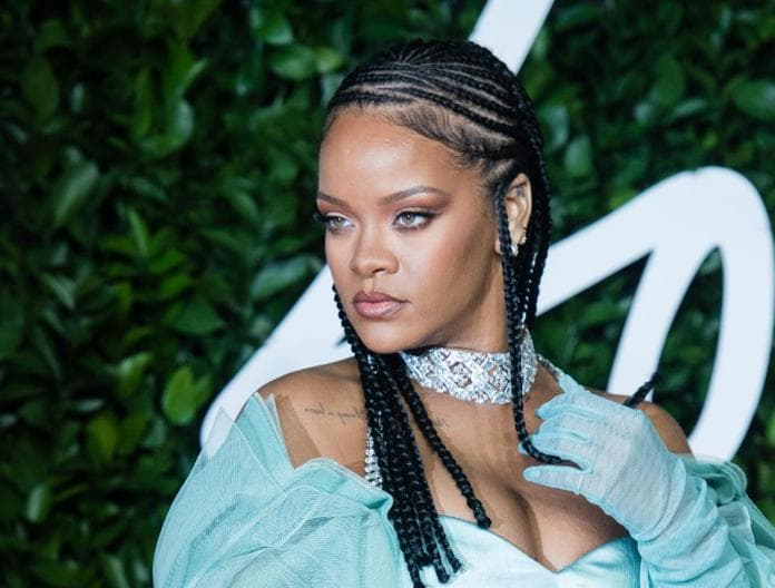 Rihanna- mulher negra de tranças, usando vestido e luvas cor verde água- olhando para frente 
