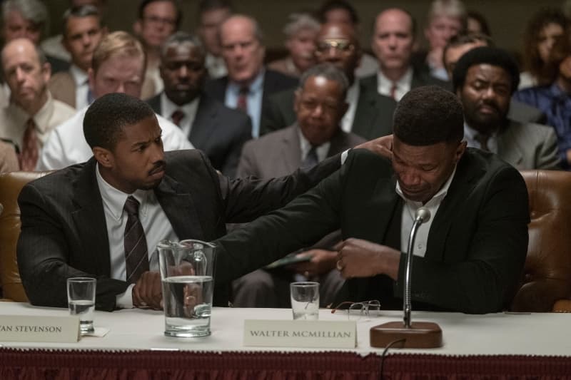 Cena do filme 'Luta por Justiça', onde o advogado Bryan Stevenson (Michael B. Jordan) e o acusado Walter (Jamie Foxx) estão sentados no tribunal 