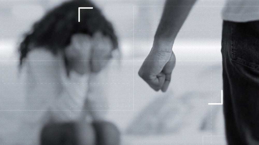 Imagem em preto e branco de um homem com o punho fechado na frente de uma mulher 