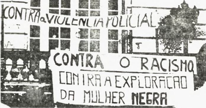 Foto em preto e branco de cartazes contra o racismo e a violência policial 